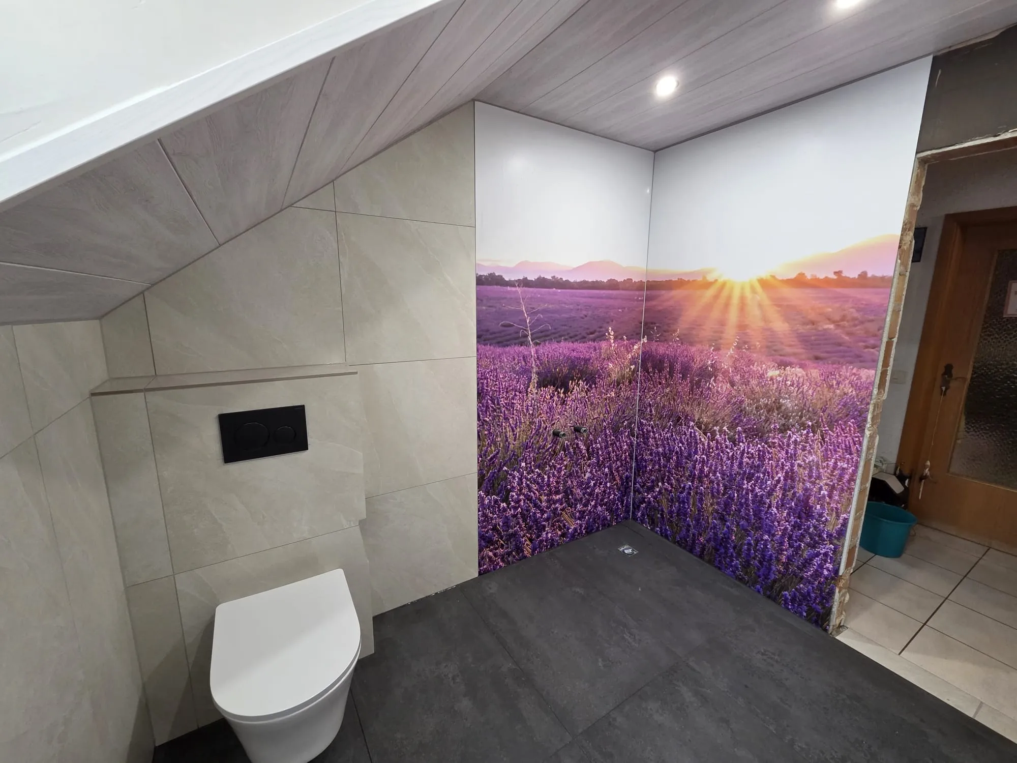Dachbad mit beiger Steinoptik, wandhängendem WC und Lavendel-Motivwand