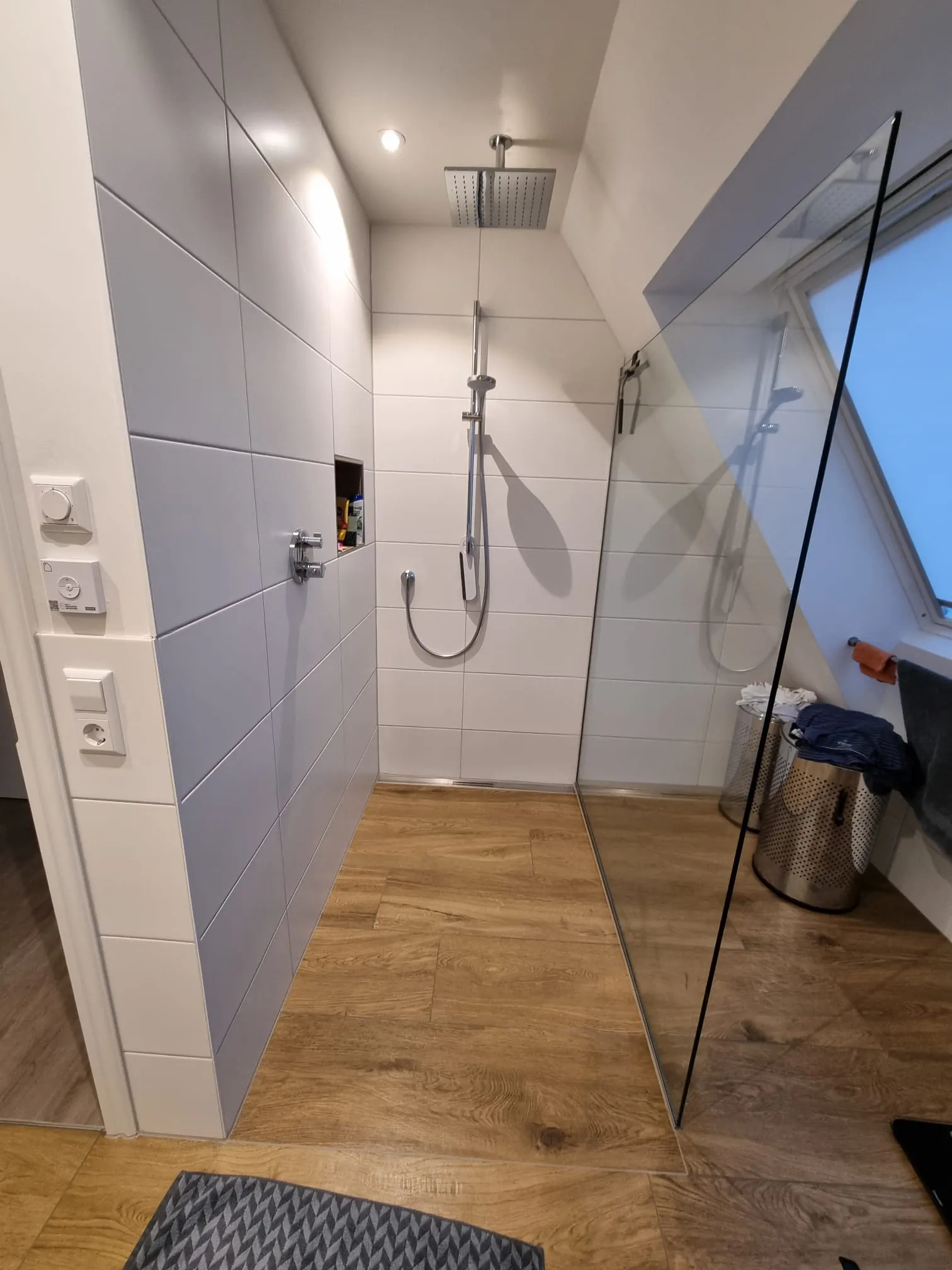 Helles Dachbad mit bodenebener Walk-in-Dusche, Glaswand und Holzoptik-Boden